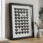 Cuadro Dos en Uno de corazones de origami negros con iniciales personalizadas, en marco negro sobre una balda de madera