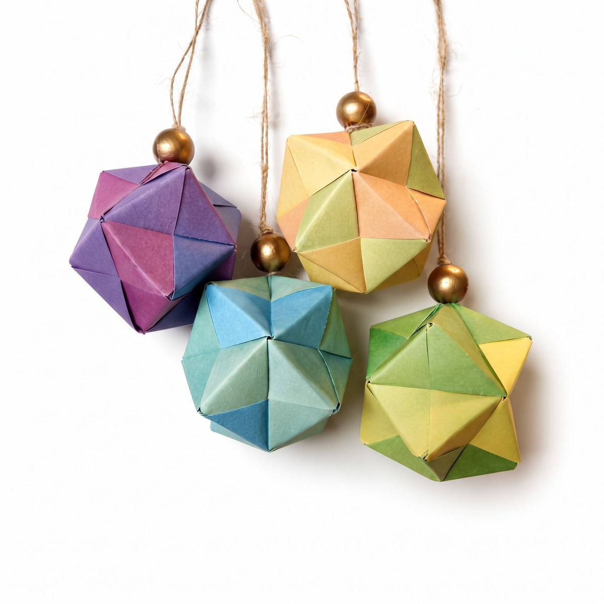 Cuatro esferas de origami morada, naranja, azul y verde colgadas de cordeles