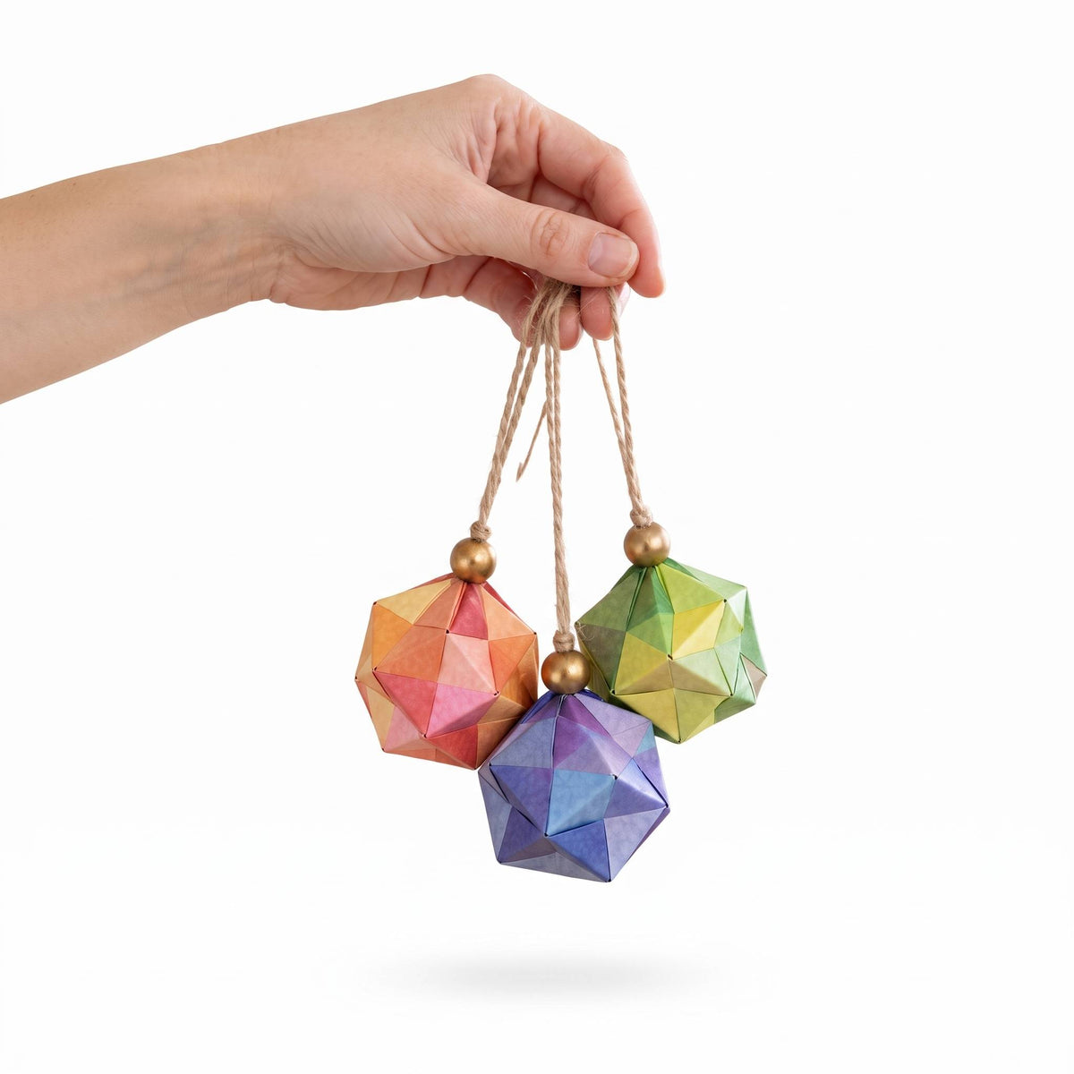 Mano sosteniendo un racimo de esferas de origami de colores con cuentas doradas