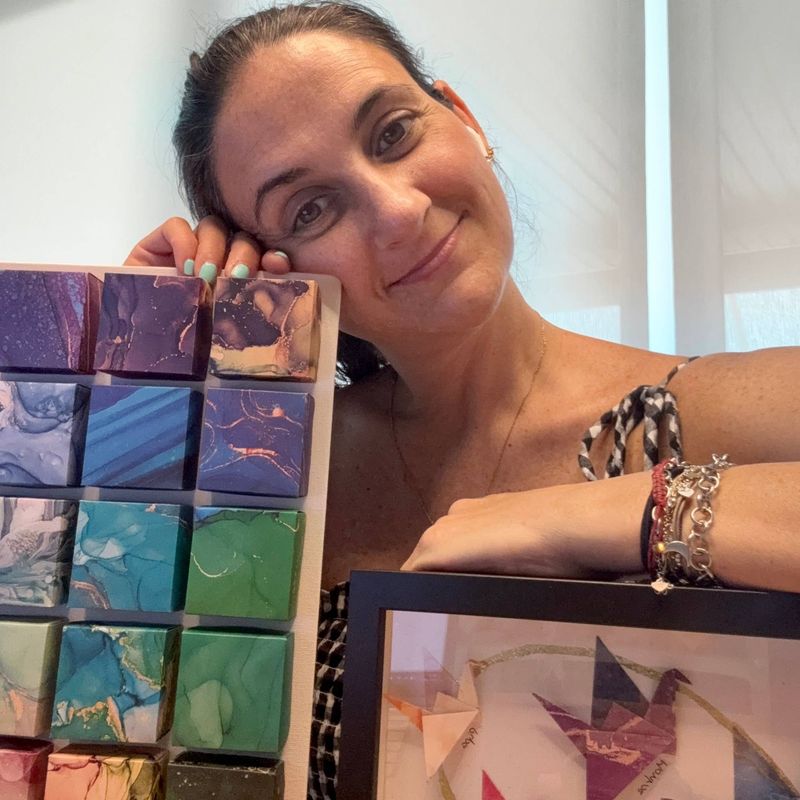 Mon, fundadora de MÖMÖ Lab, sonriendo apoyada sobre sus cuadros de origami modular de colores